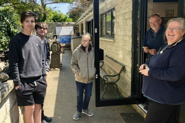 An image of three students from All Saints School, Weymouth working at Portland Museum, lead by Trustees Nancy Grace and Nick Reed.