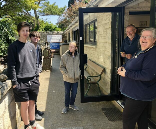An image of three students from All Saints School, Weymouth working at Portland Museum, lead by Trustees Nancy Grace and Nick Reed.